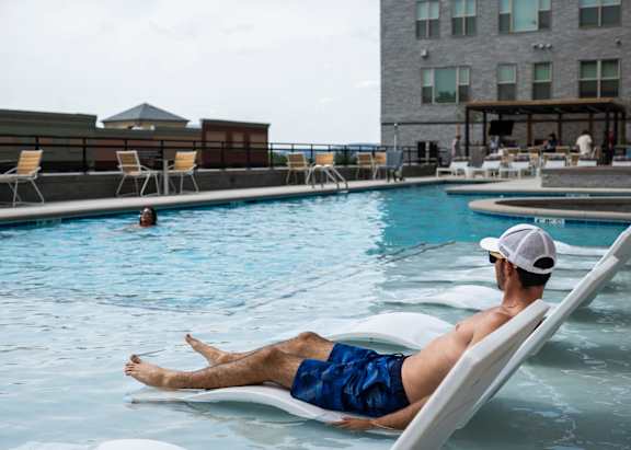 A man relaxes on a sun lounger by a pool.