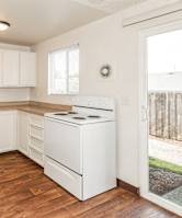 A white kitchen with wooden floors and white appliances.