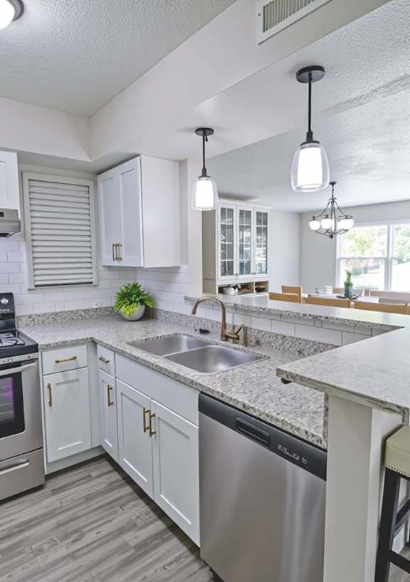 A kitchen with a stove, sink, and bar stools.