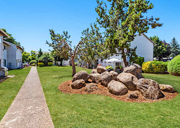 a large rock sits in the middle of a grassy area with trees in the background