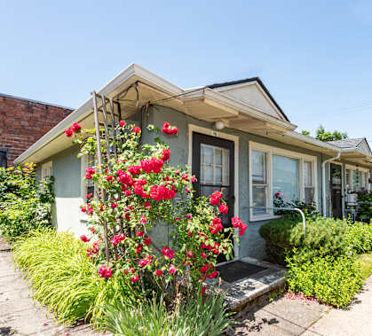 A house with a flower bed in front of it.