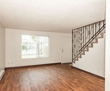 A room with a wooden floor and a staircase with a metal railing.