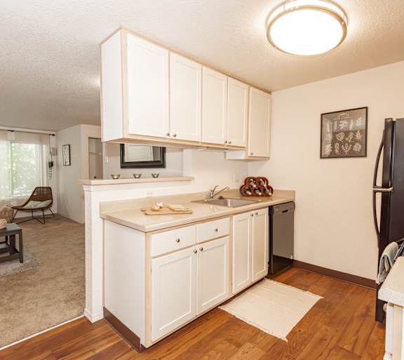 Kitchen and living room view with white cabinetry at Clackamas Trails Apartments in Clackamas, OR