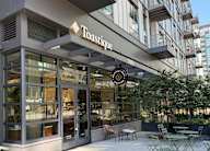 The exterior of a Toastique store with a glass facade and outdoor seating area.