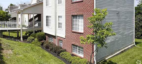 A two-story house with a red brick exterior and a grey siding.