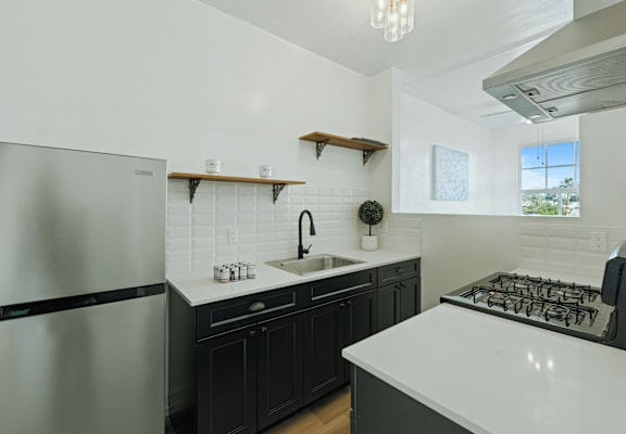 A modern kitchen with a stainless steel refrigerator and a white countertop.