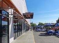A sunny day at the outdoor market with blue umbrellas and tables.