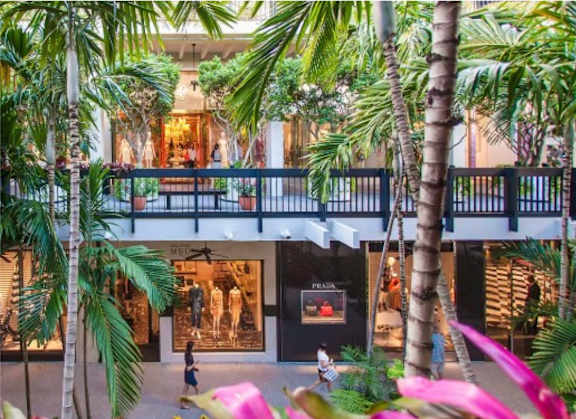 A shopping mall with a balcony and palm trees.
