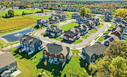 A bird's eye view of a residential neighborhood with houses and a pond.