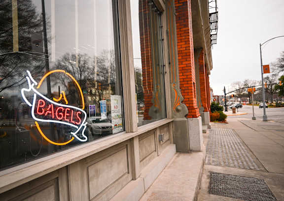 A bagel shop with a neon sign in the window.