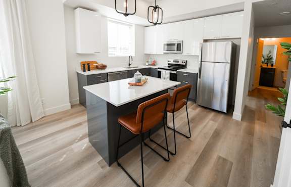 A modern kitchen with a white island and wooden floors.