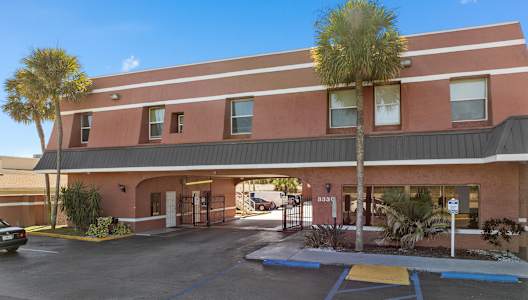 a red building with a parking lot and palm trees