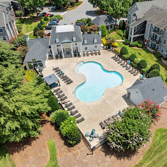 A large swimming pool surrounded by a patio and a small garden.