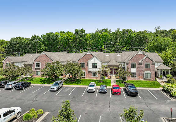 A parking lot in front of a building with cars parked.