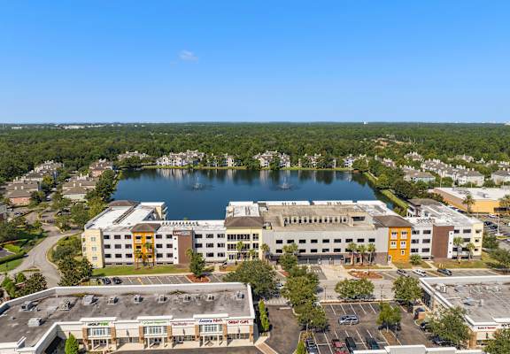 A large building with a yellow door is surrounded by a parking lot at Lake Lofts at Deerwood, Jacksonville, FL, 32216