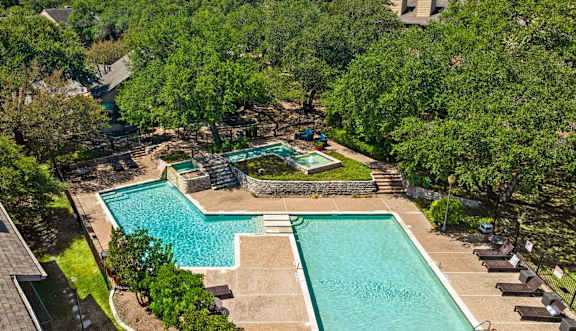 A large swimming pool with lounge chairs and a building in the background.