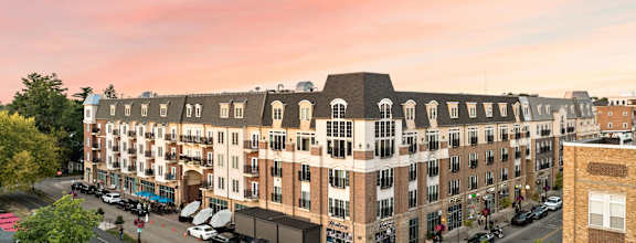 A large building with a lot of windows is surrounded by trees and cars. at Sophia Square Apartments, Carmel, IN, 46032
