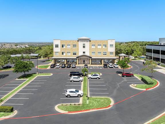 A parking lot with cars and a building in the background.
