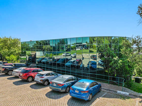 A parking lot with cars parked in front of a glass building.