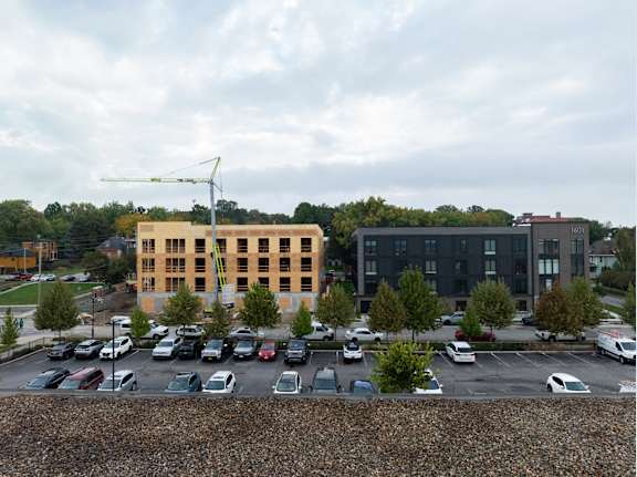 A parking lot with cars and two buildings in the background.