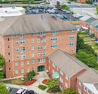 an aerial view of a brick building with trees and a parking lot
