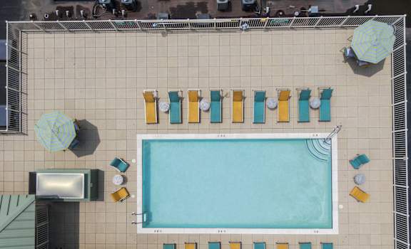 an overhead view of a swimming pool with pool chairs and a television