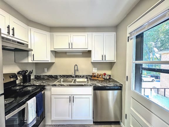 a small kitchen with white cabinets and a window