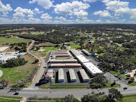 A large industrial building complex is surrounded by a grassy field and a road.