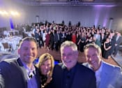 Thumbnail 12 of 21 - A group of people are taking a selfie in a large room.