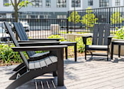 Thumbnail 4 of 8 - A black chair and table are on a wooden deck.