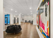 Thumbnail 2 of 8 - A large painting with black, pink, orange and yellow colors hangs on the wall.