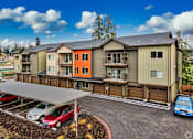 Thumbnail 8 of 8 - A parking lot with cars and a building in the background.