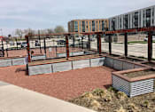 Thumbnail 1 of 10 - A garden with a pergola and raised beds in front of a building.