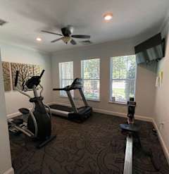 a home gym with exercise equipment and a ceiling fan