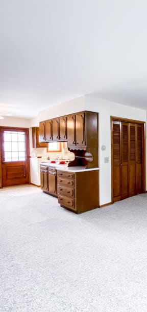 an empty living room with a staircase and a kitchen