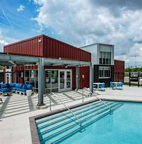 A pool area with a red building and blue seating.at Linc, Des Moines Iowa
