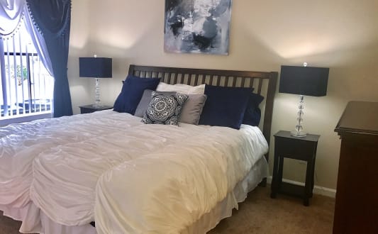 a bedroom with a large bed with a white comforter and blue pillows