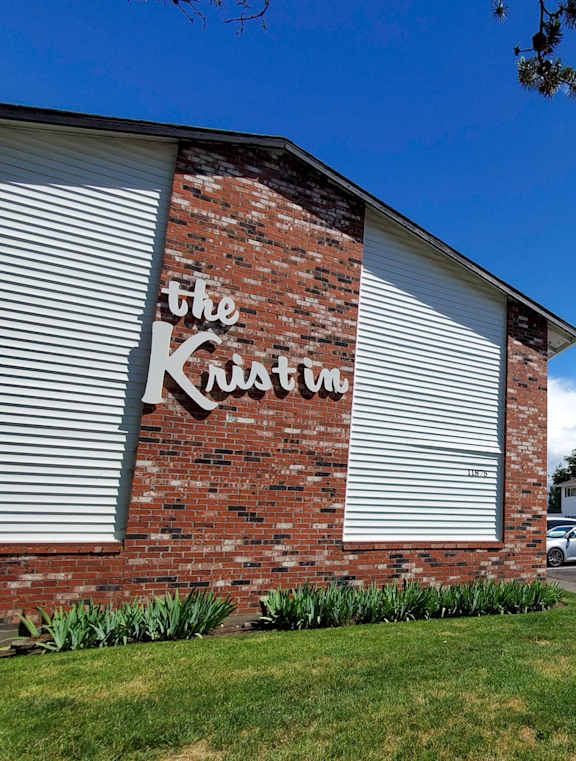 The Kristin House is a residential building with a brick wall and a sign on it.