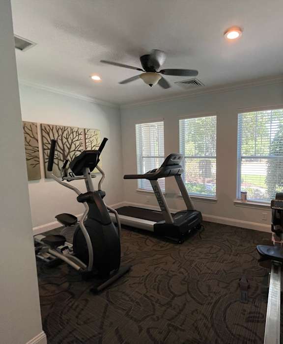 a home gym with exercise equipment and a ceiling fan