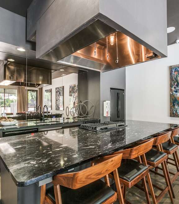 A modern kitchen with a large island and wooden chairs.