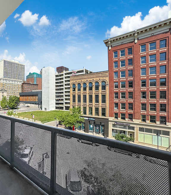 A balcony with a mesh screen overlooking a cityscape.