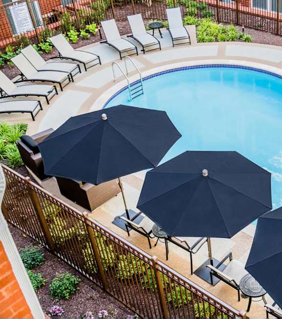 A pool surrounded by a black fence with blue umbrellas.