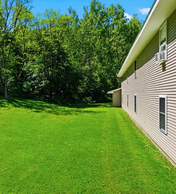 A house with a green lawn and trees in the background.