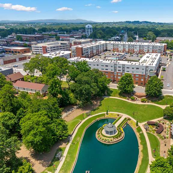 A large building complex with a fountain in the middle of a green area.