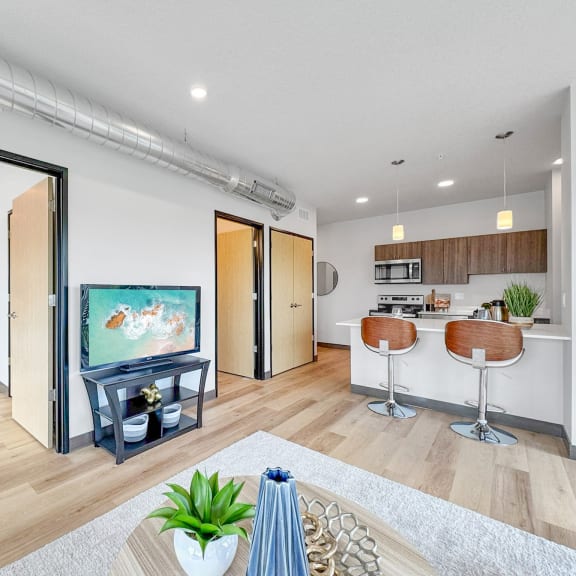 a living room with a tv and a kitchen with a table and chairs