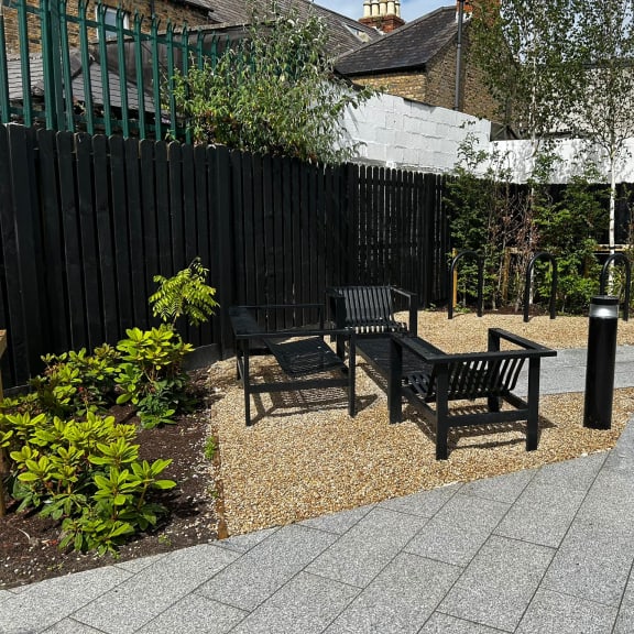 a courtyard with two benches and a table in front of a fence