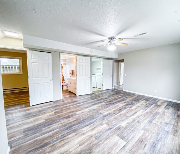 an empty living room with wood floors and a ceiling fan