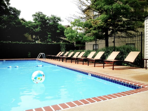 a pool with chairs and a beach ball in the water