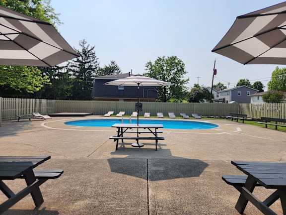 A pool with a table and chairs and umbrellas in the foreground.