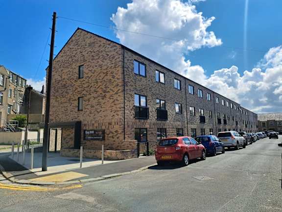 A long brick building with cars parked in front.